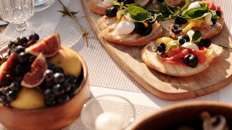 Sunlit outdoor table with Mediterranean bruschetta and fresh fruit display.